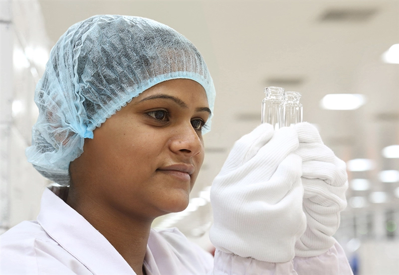 An employee at SCHOTT Kaisha’s production facility in Jambusar inspects two glass vials